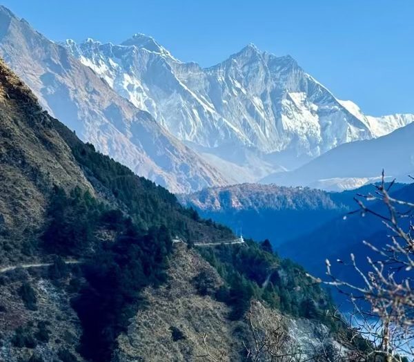 A stunning panoramic view of Mount Everest and Lhotse, seen from the Everest View Trek, with clear blue skies and rugged Himalayan terrain.