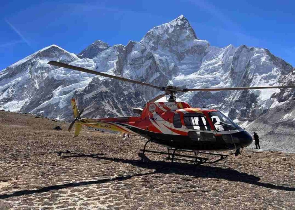 Helicopter landed at Everest Base Camp with Mount Everest and Himalayan peaks in the background.
