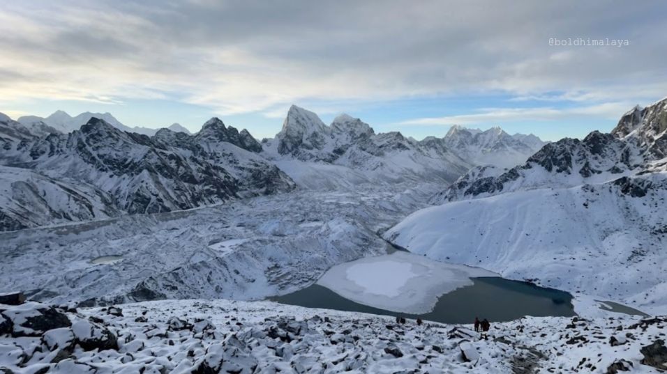Frozen Gokyo Lake, covered in thick ice and snow, surrounded by towering Himalayan peaks, during Gokyo Lake Trek