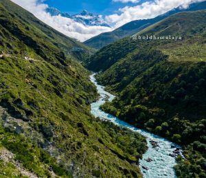 Scenic Himalayan valley with a turquoise river flowing between green mountain slopes on the Everest Base Camp trekking route.