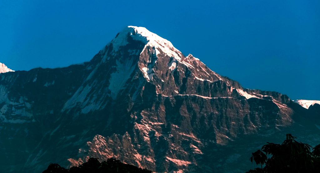 Snow-covered summit of Dhaulagiri I rising above rugged rocky slopes, one of the 14 highest mountains in the world