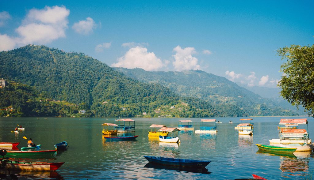 Scenic view of Phewa Lake with colorful boats and reflections of the Annapurna Range in Pokhara, one of the best things to do in Nepal