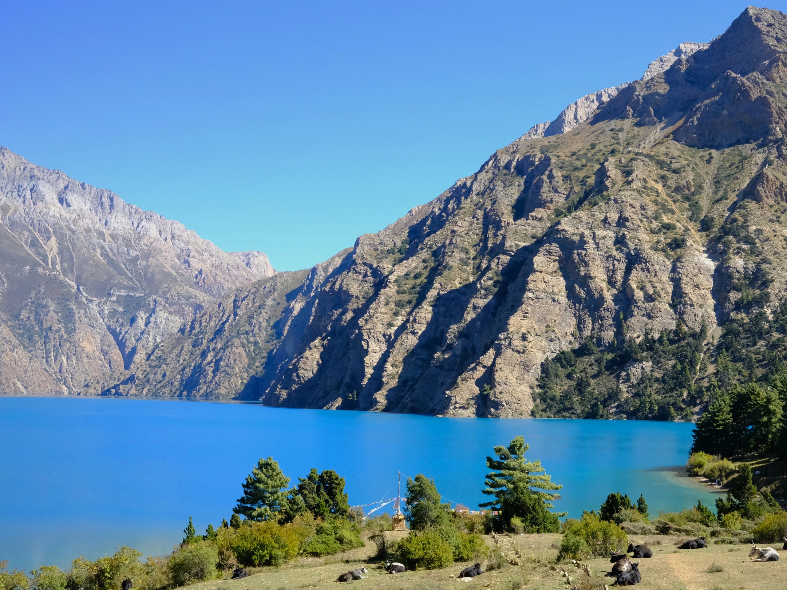 Shey Phoksundo Lake with turquoise blue water surrounded by rugged cliffs and Himalayan mountains during the Lower Dolpo Circuit Trek