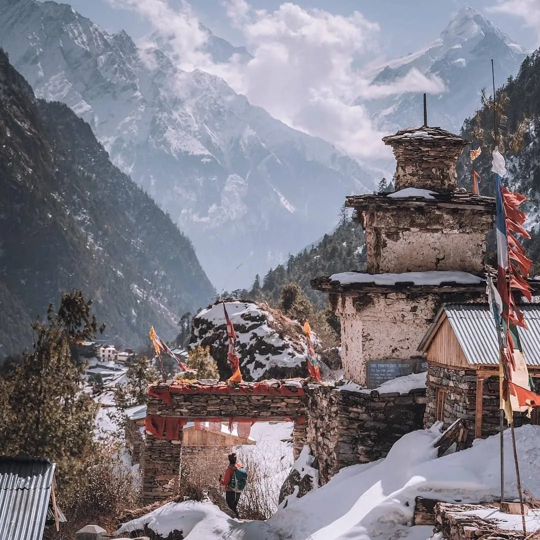 Trekkers crossing traditional Buddhist chorten and gateway on the Manaslu Circuit Trek in Nepal