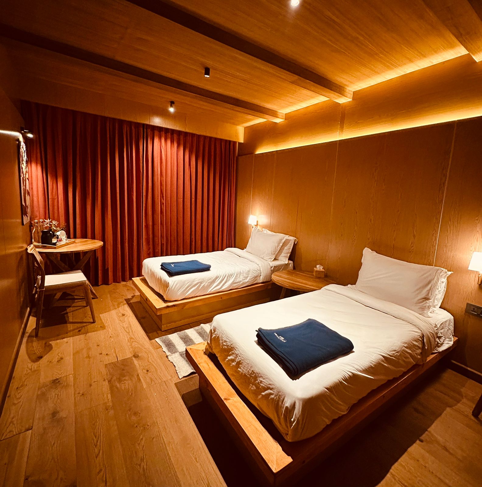 Twin bedroom with wooden interiors, warm lighting, and modern furnishings at a luxury Himalayan lodge on the Luxury Everest Base Camp Trek with Helicopter Return.