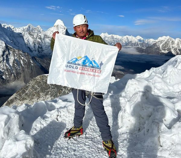Climber holding Bold Himalaya flag at the summit during Everest Base Camp Trek with Island Peak Climbing in the Everest region of Nepal.