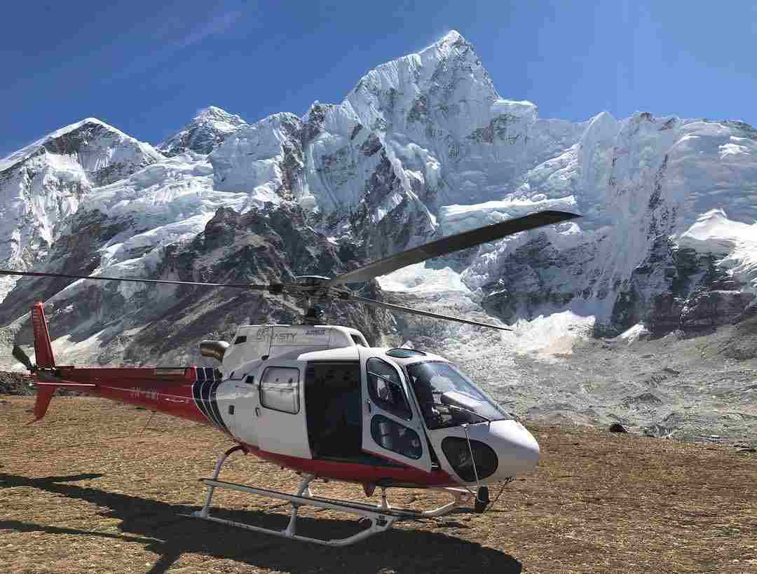 Aerial view of a turquoise glacial lake surrounded by snow-capped Himalayan mountains during an Everest Helicopter Tour in Nepal.