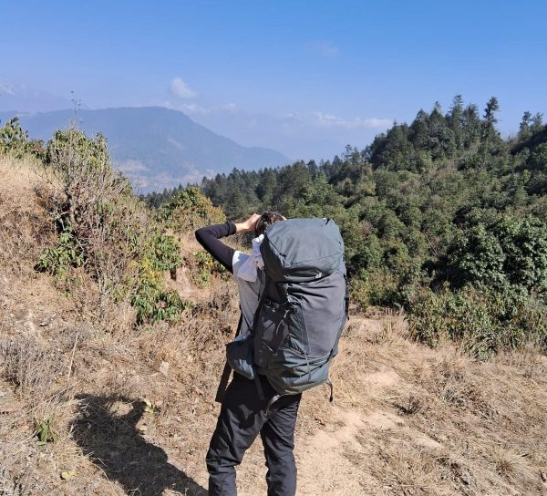 Hiker with backpack enjoying a clear mountain viewpoint on the Pikey Peak Trek in Nepal.
