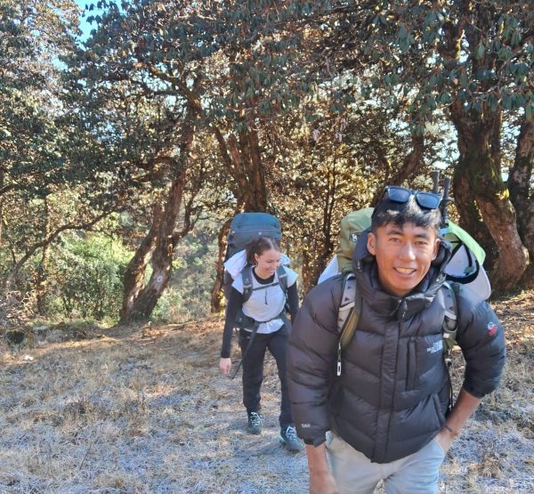Trekker and guide walking through forested trail on the Pikey Peak Trek in Nepal’s Lower Everest region.