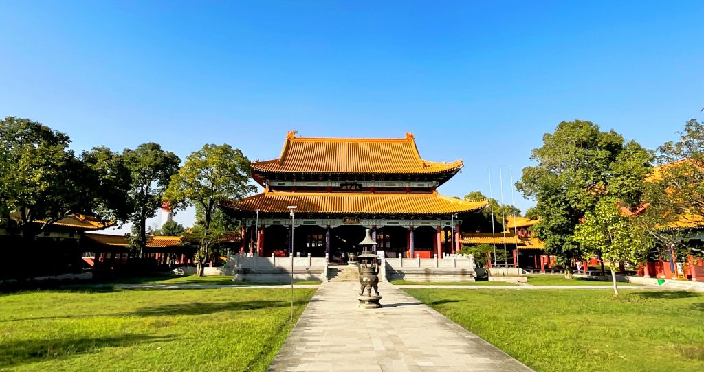 Visit a traditional Chinese Buddhist monastery with bright red walls and orange pagoda-style roofs, one of the things to do in Lumbini