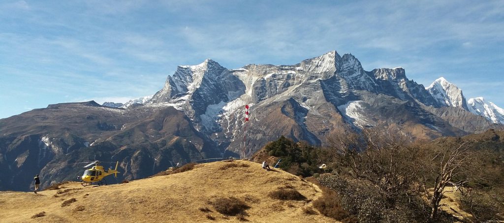 A yellow helicopter landed in the Everest region, with dramatic snow-capped Himalayan peaks rising sharply