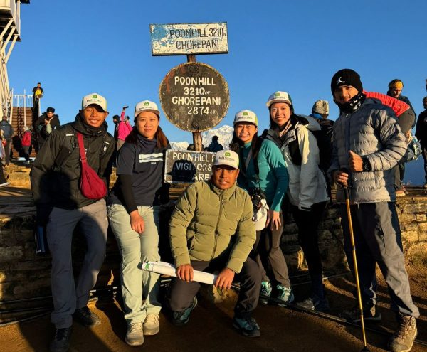 A group of trekkers smiling together at the Ghorepani Poon Hill, standing in front of the signboard at 3,210 meters during sunrise, one of the best winter treks in Nepal-Best Hiking Trails Around Pokhara Valley