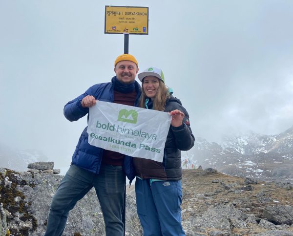 Two trekkers holding Gosaikunda trek banner in snowy Langtang region Nepal during winter trek
