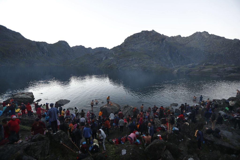 Pilgrims taking a holy bath at Gosaikunda Lake during the Janai Purnima Festival in Nepal, surrounded by snow-capped Himalayan mountains-Helicopter Tours from Kathmandu