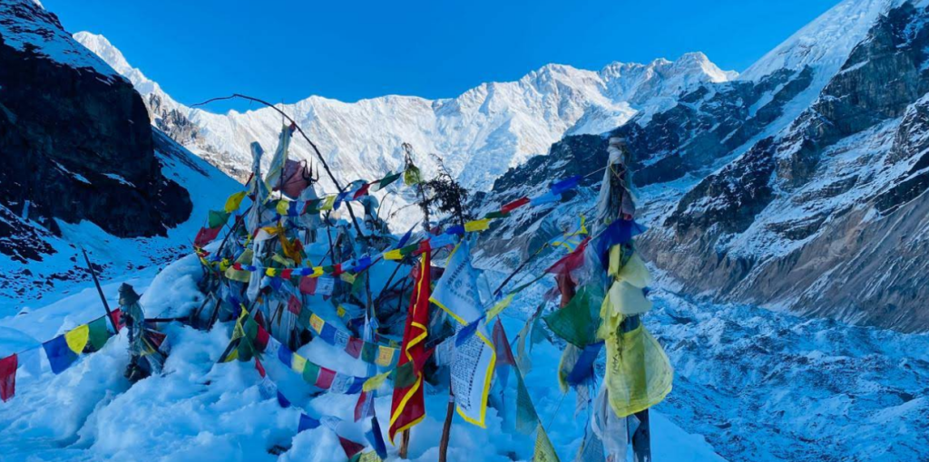 Prayer flags at Kanchenjunga Base Camp overlooking a glacier and snow-covered Himalayan peaks in eastern Nepal.