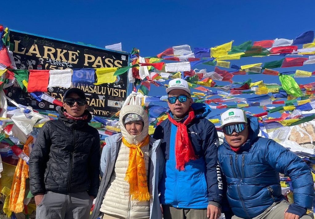 Trekkers celebrating at Larke Pass, with prayer flags, one of the best high pass treks in Nepal