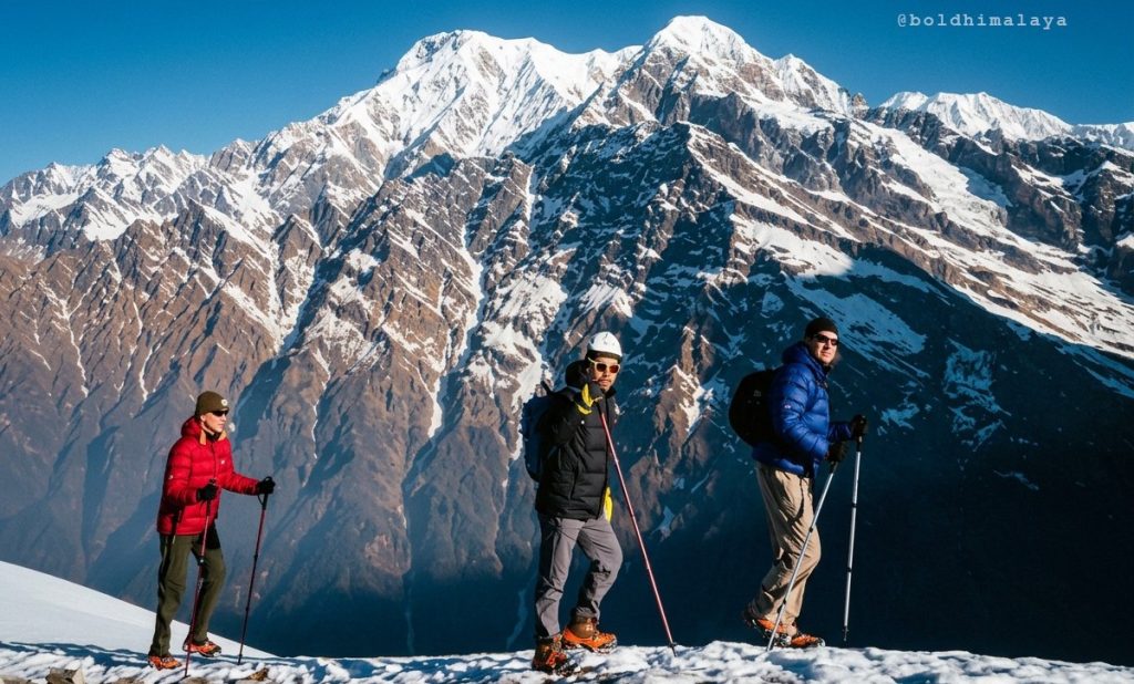 Trekkers trekking along a scenic mountain trail with snow-capped mountains in the background.