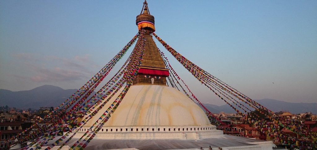 Bouddhanath Stupa in Kathmandu, decorated with colorful prayer flags during sunset, is a major spiritual landmark featured in many Nepal travel guide highlights
