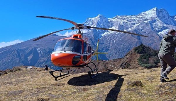 A red helicopter landed on a high-mountain viewpoint during the Everest View Trek, highlighting a premium experience for luxury trekking in Nepal