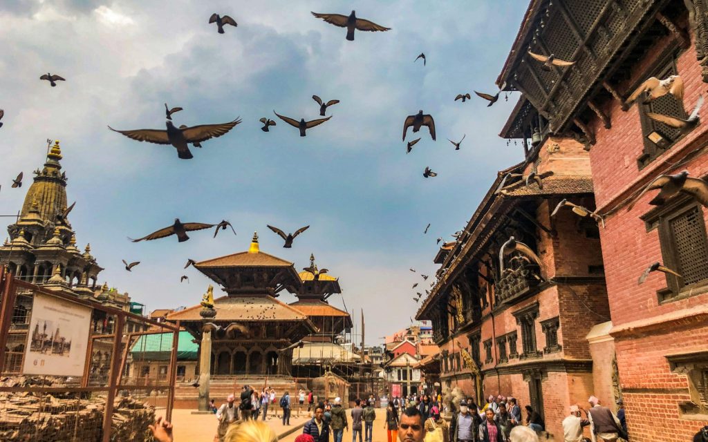 Historic Patan Durbar Square in Kathmandu Valley, with ancient temples and pigeons flying overhead, is one of the best tourist places to visit in Nepal