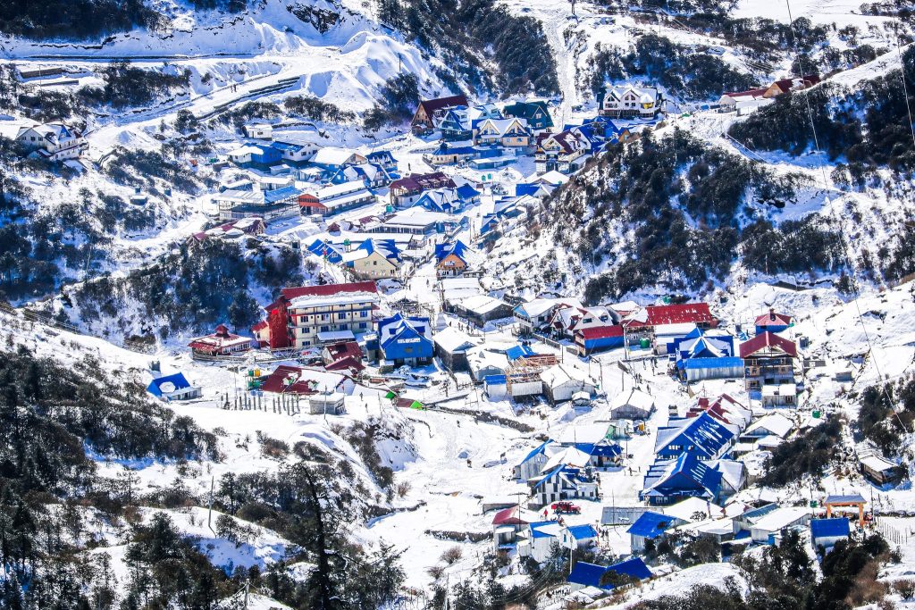 Stunning view of Kuri Village in the Himalayas captured during a Helicopter Tour from Kathmandu, featuring snow-capped roofs and surrounding mountains.