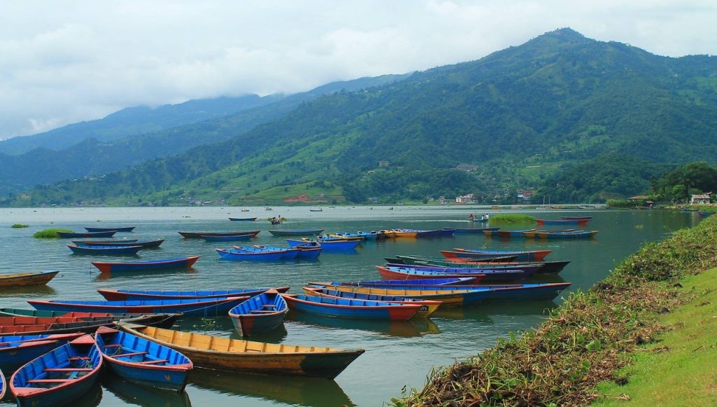 Tranquil scenes at Phewa Lake in Pokhara, where vibrant boats against the backdrop of serene landscapes, are one of the must-visit highlights in the Nepal travel guide