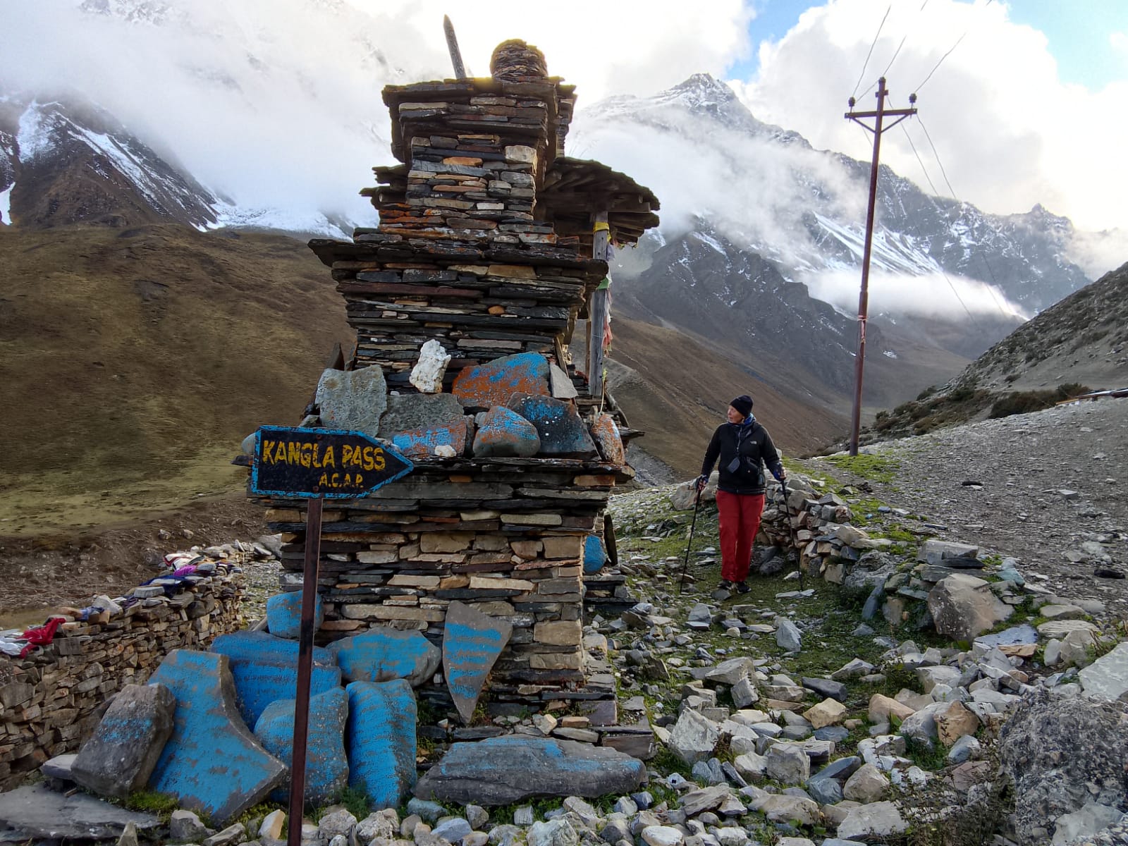 Trekkers heading to Kang La Pass at 5,306 m / 17,400 ft, passing a Tibetan Buddhist Chorten on the Nar Phu Valley Trek in Nepal