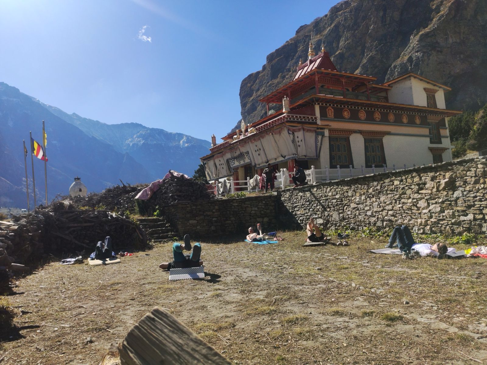 Trekkers practicing yoga at Nar Phedi in Nar Phu Valley with Himalayan mountains in the background during the trek in Nepal