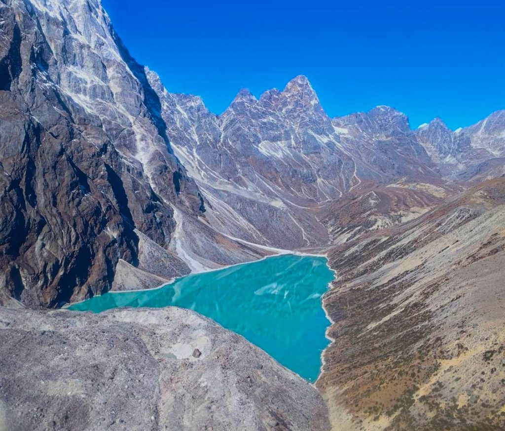 Turquoise Gokyo Lake, surrounded by rugged Himalayan peaks during an Everest Base Camp helicopter tour