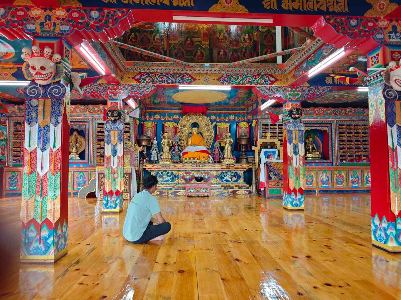 Trekkers visiting Tengboche Monastery during the Everest Base Camp Trek by Road, surrounded by colorful Buddhist art and sacred statues.