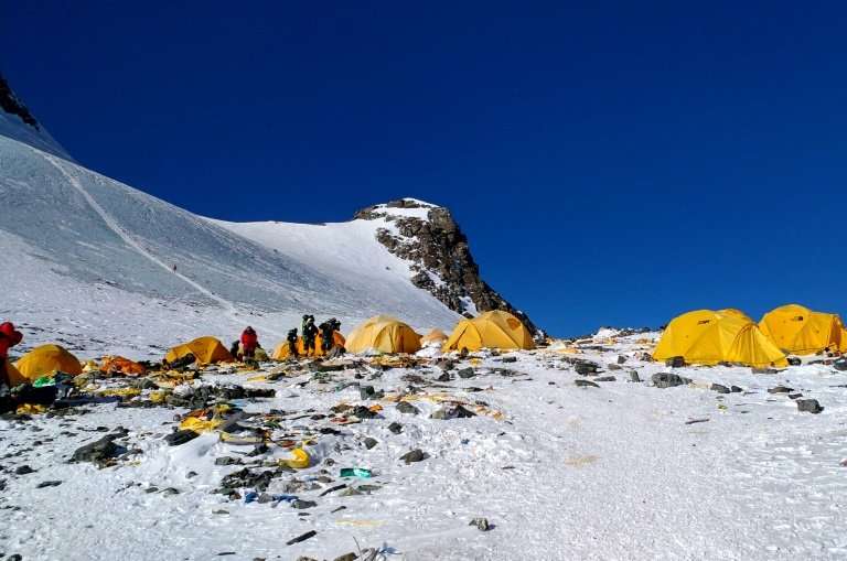 High-altitude tents and climbers at Rainbow Valley on Mount Everest with snow and scattered gear in the death zone.