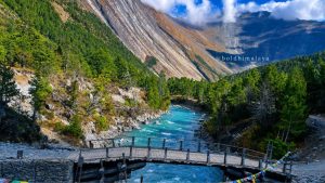 Suspension bridge over a flowing river with scenic mountain landscape on the Annapurna Circuit trek near Tilicho Lake