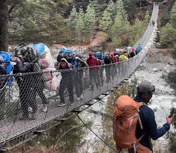 Trekker crossing suspension bridge on the way to Lobuche Peak Climb, Nepal Himalaya