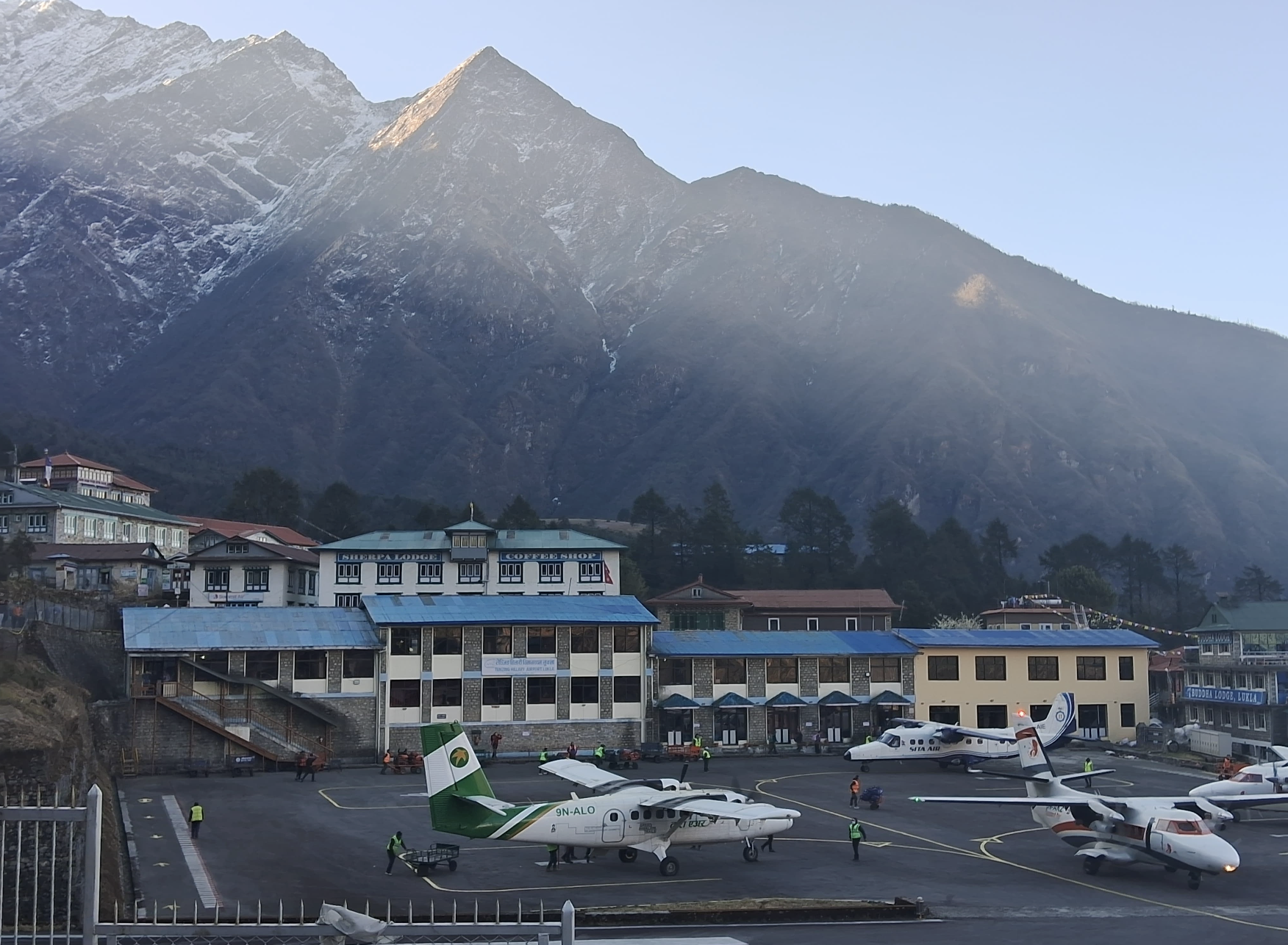 Small aircraft lined up on the runway at Lukla Airport, ready for takeoff with mountain backdrop during Gokyo Lakes Renjo La Pass Trek