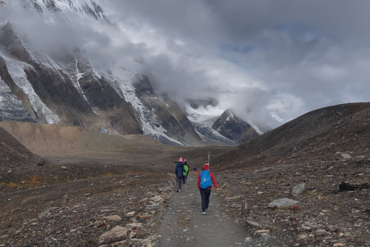 Trekkers hiking the Annapurna Circuit towards Tilicho Lake, surrounded by towering Himalayan peaks, snow-capped mountains, and rugged trails in Nepal.