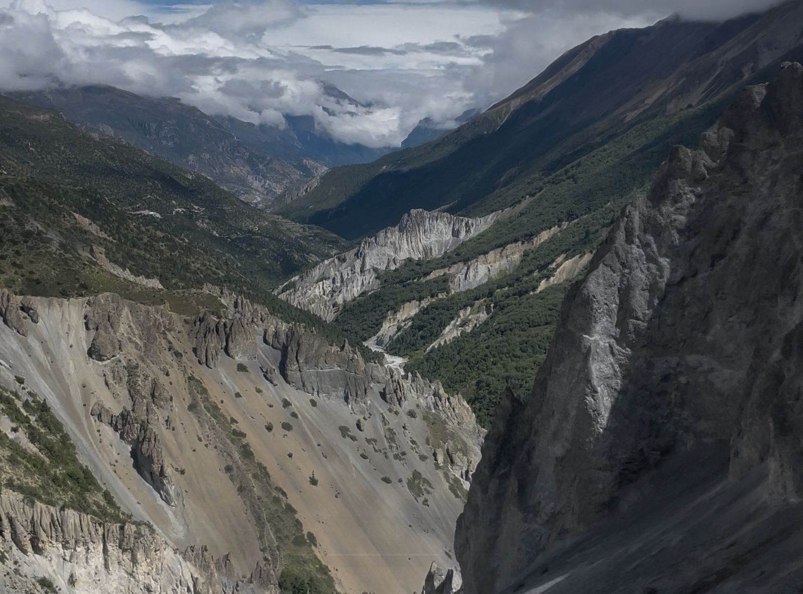 Scenic mountain landscape of Manang Valley with rugged cliffs and green hills along the Annapurna Circuit trekking route in Nepal.