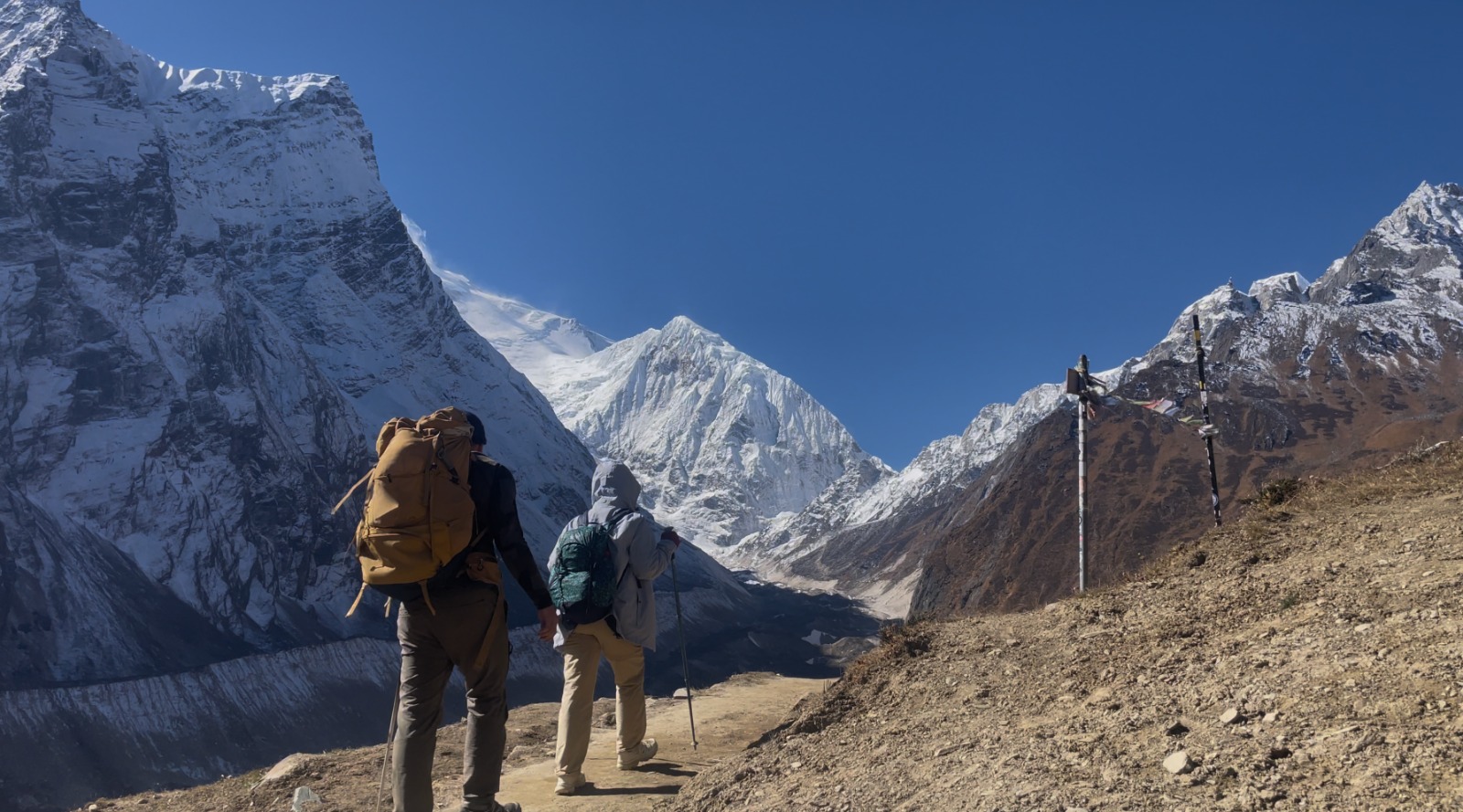 Two trekkers enjoying panoramic views on the Manaslu Circuit Trek Larke La Pass, Nepal, with snow-covered mountains in the background.