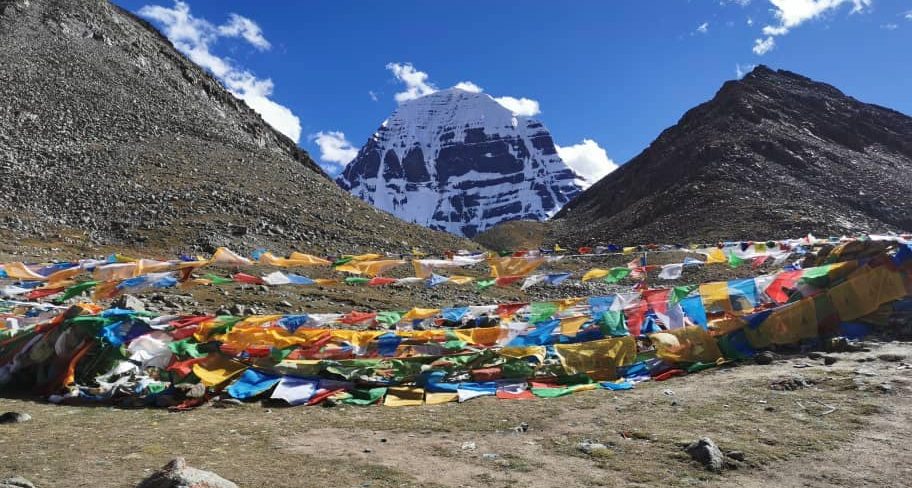 Mount Kailash surrounded by colorful prayer flags during the Kailash Mansarovar Yatra, reflecting spiritual significance and Kailash Mansarovar Yatra cost considerations