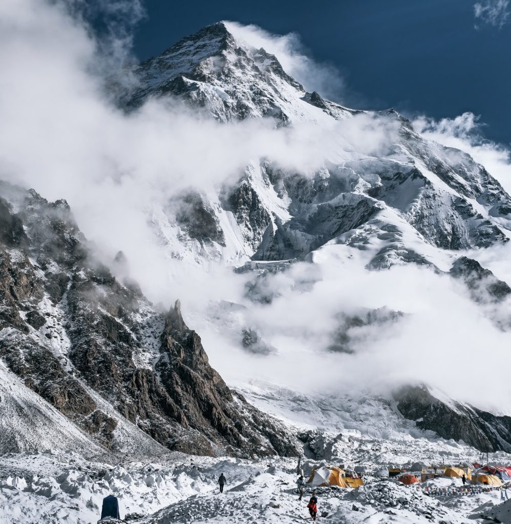 K2 mountain peak covered in snow with clouds and tents at base camp on Baltoro Glacier during K2 Base Camp Trek.