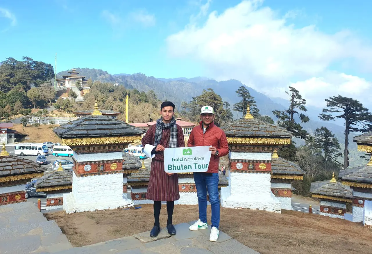 Travelers standing near traditional Bhutanese stupas with mountain views during a Nepal Bhutan luxury tour package.