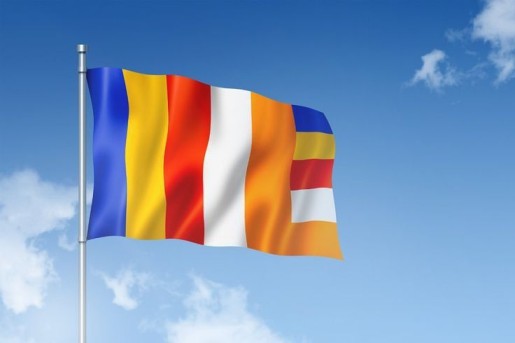 Buddhist flag meaning with colorful vertical stripes waving against a clear blue sky
