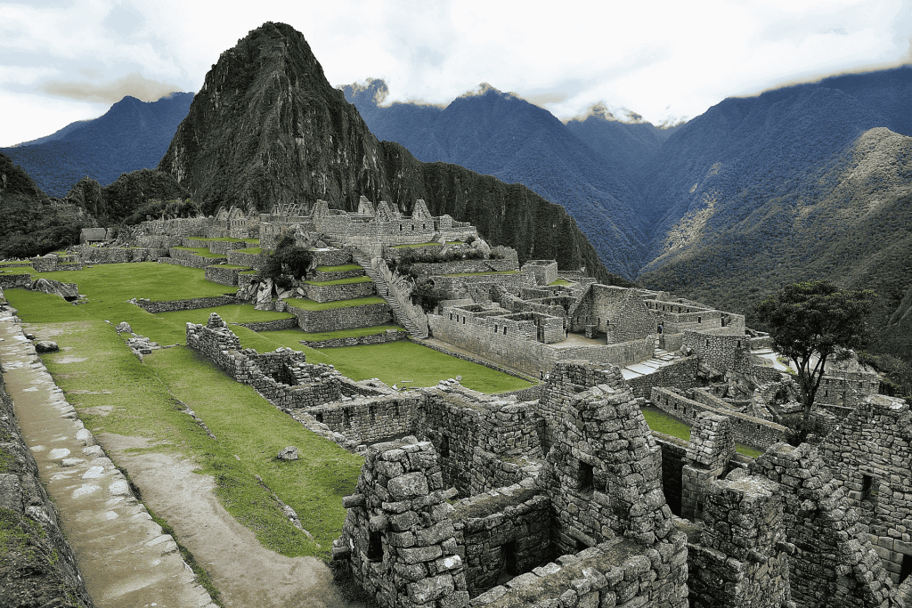 Ancient stone ruins of Machu Picchu with green terraces and towering Andes mountains viewed from the Inca Trail in Peru
