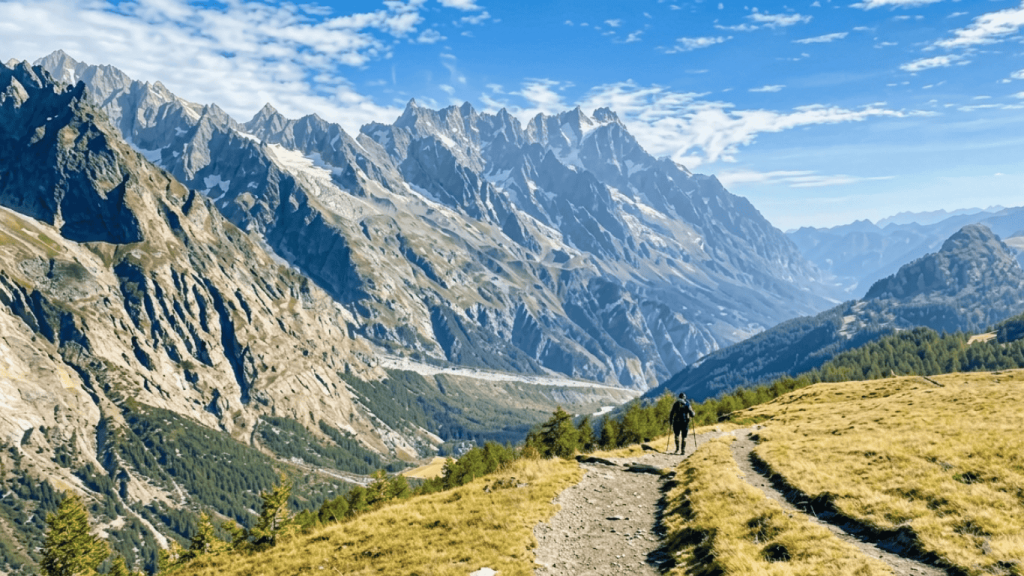 Hiker walking along scenic trail on Tour du Mont Blanc with panoramic views of the Mont Blanc mountain range