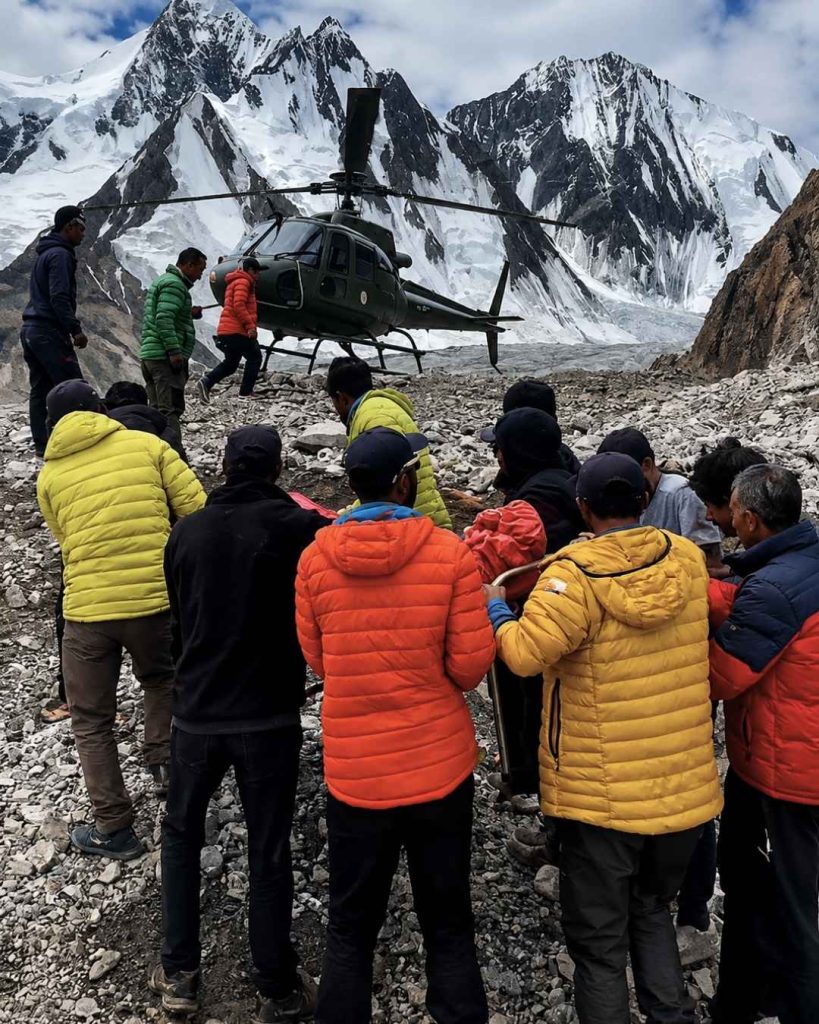 Rescue team carrying dead bodies toward a helicopter during Broad Peak avalanche rescue in the Karakoram mountains.