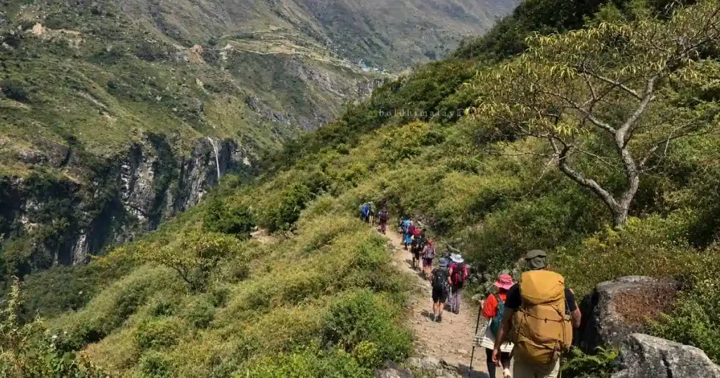 A group of trekkers is walking along a narrow mountain trail.